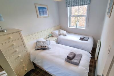 The third bedroom contains two single beds at one side of the room.